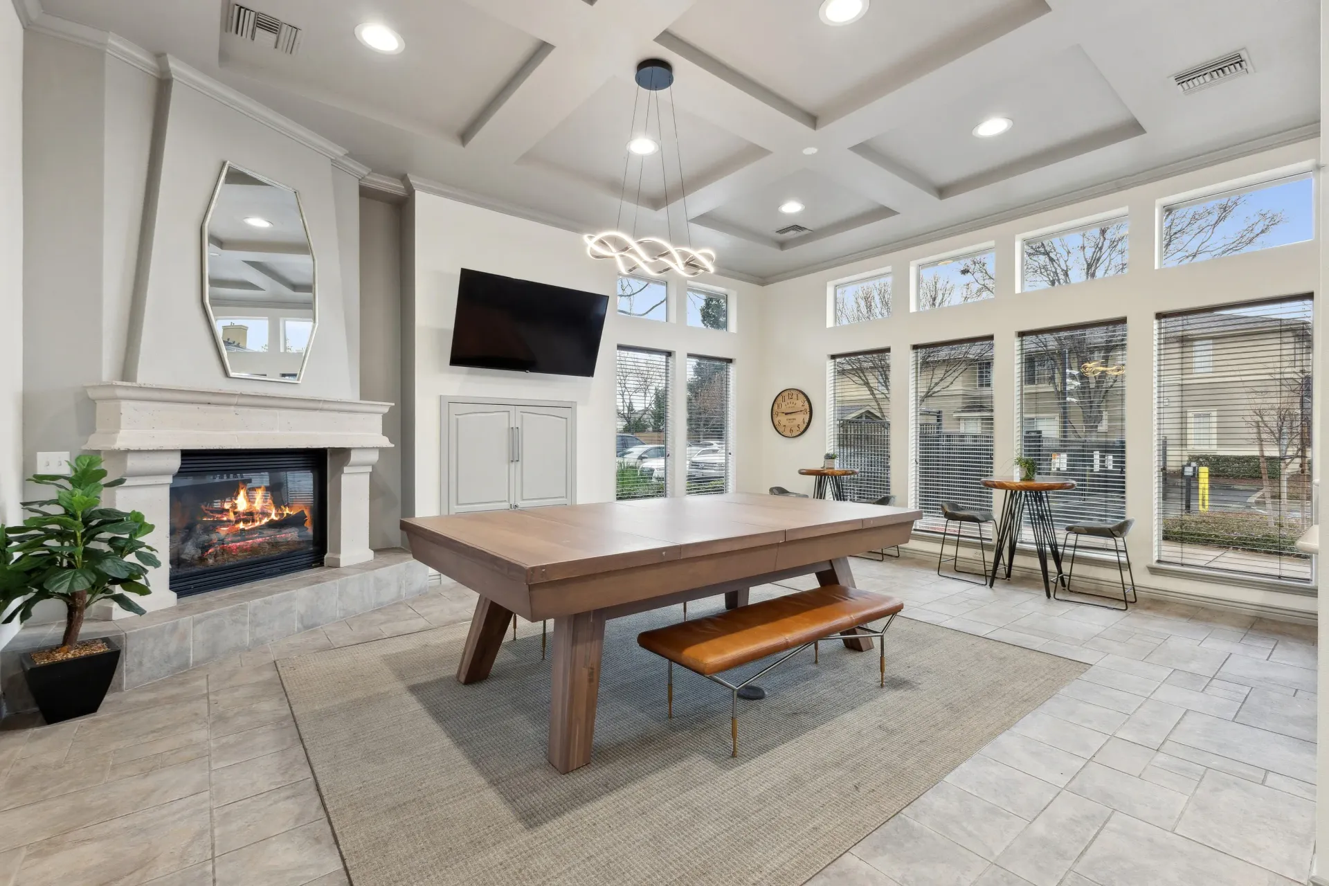 Community lounge with a lit fireplace, wall-mounted TV, and a pool table at Cross Pointe apartments in Antioch, CA.