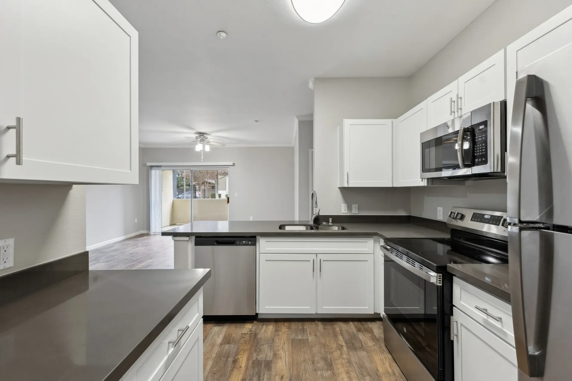 Bright kitchen with white cabinets, gray countertops, and stainless steel appliances at Cross Pointe apartments in Antioch, CA.