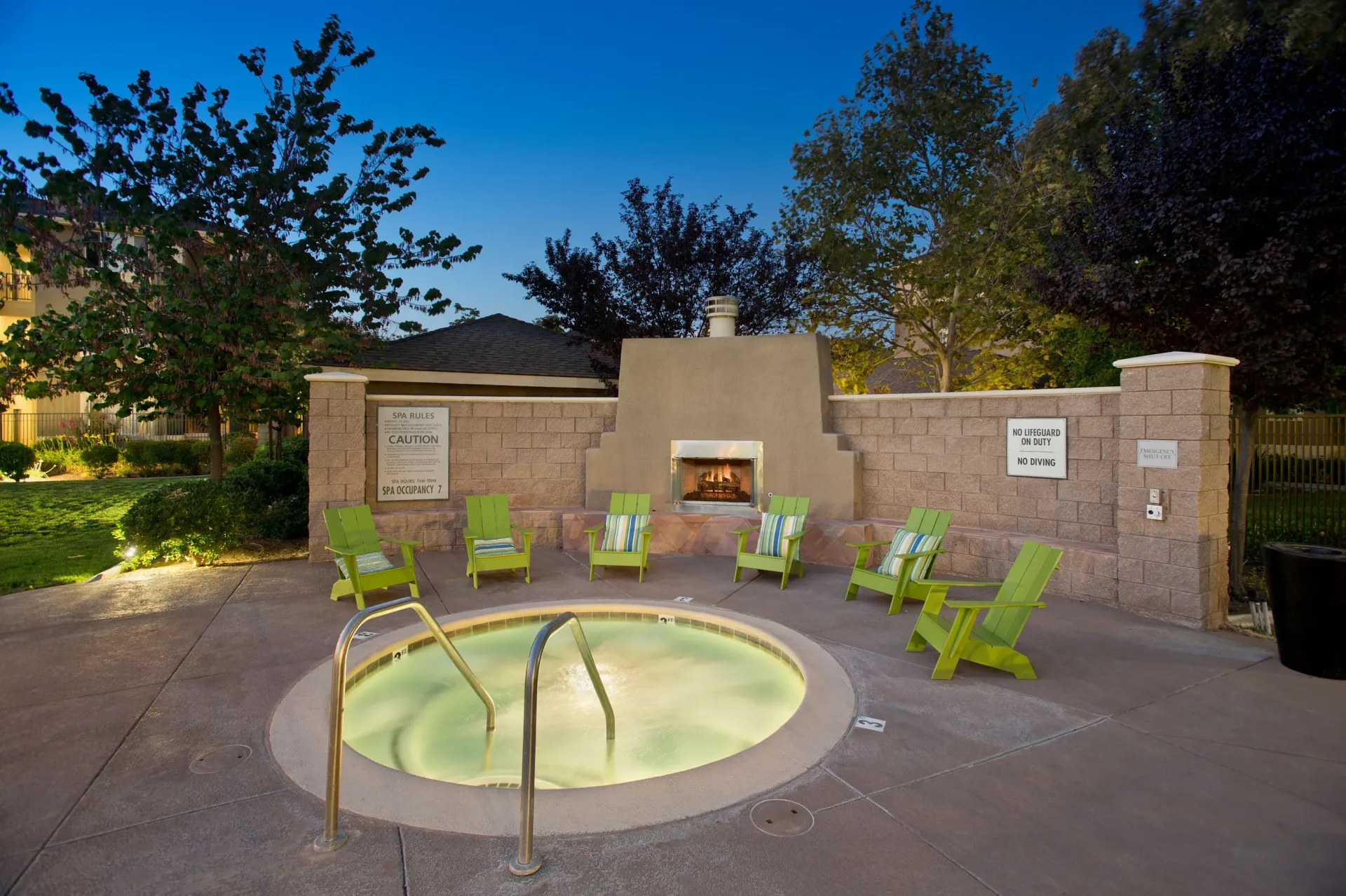 Outdoor hot tub surrounded by lime-green chairs and a central fireplace at Cross Pointe apartments in Antioch, CA.