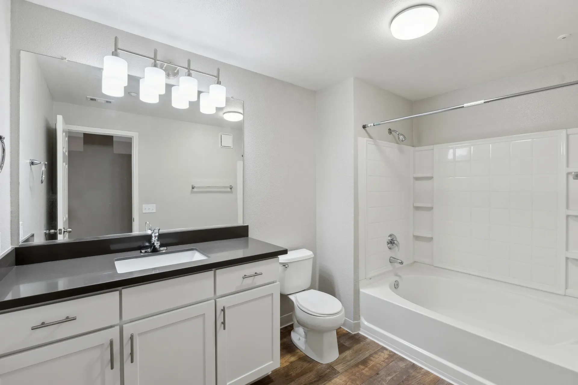 Bathroom with white vanity, large mirror, toilet, and a tub/shower at Cross Pointe apartments in Antioch, CA.