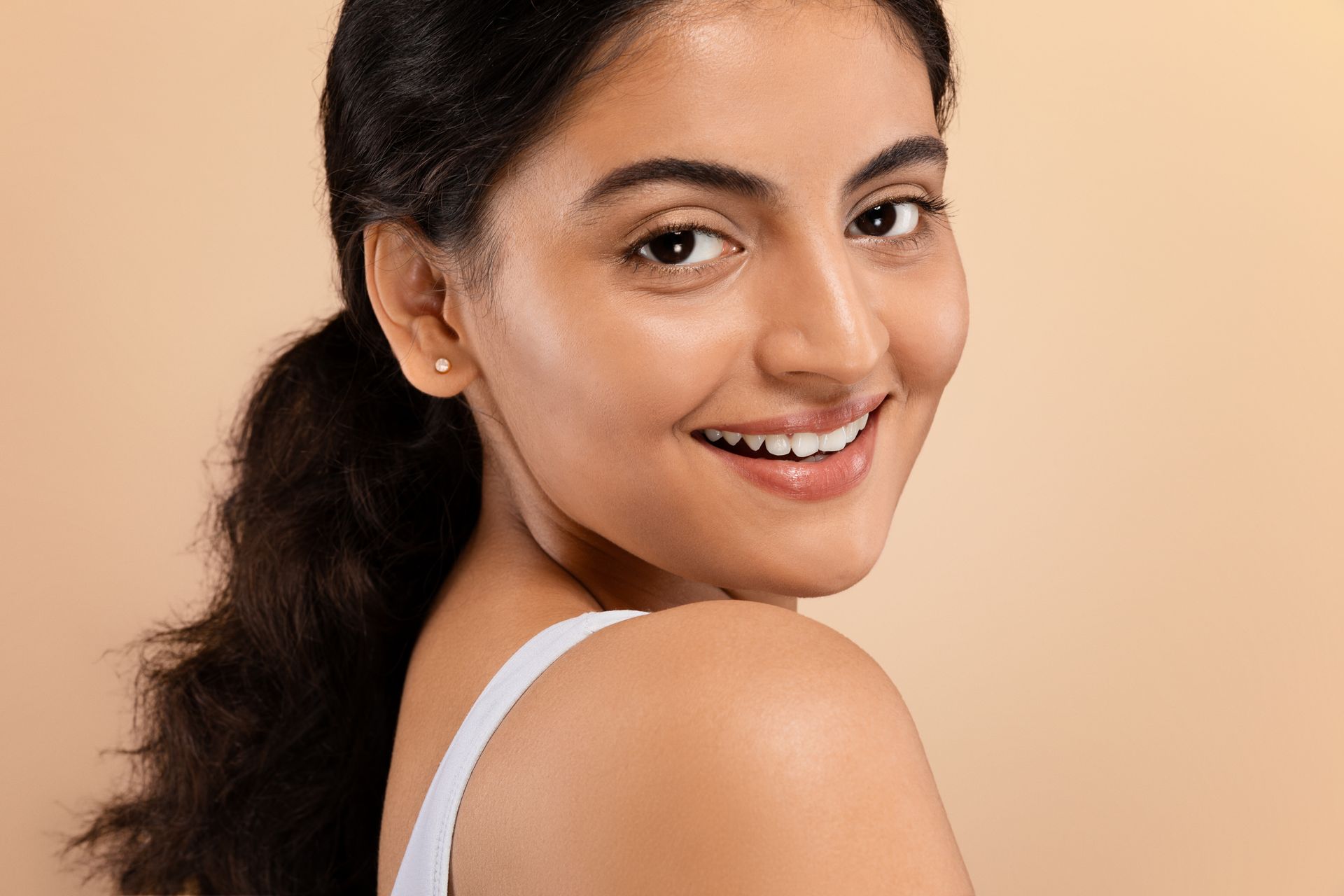 a woman is smiling and looking over her shoulder at the camera .