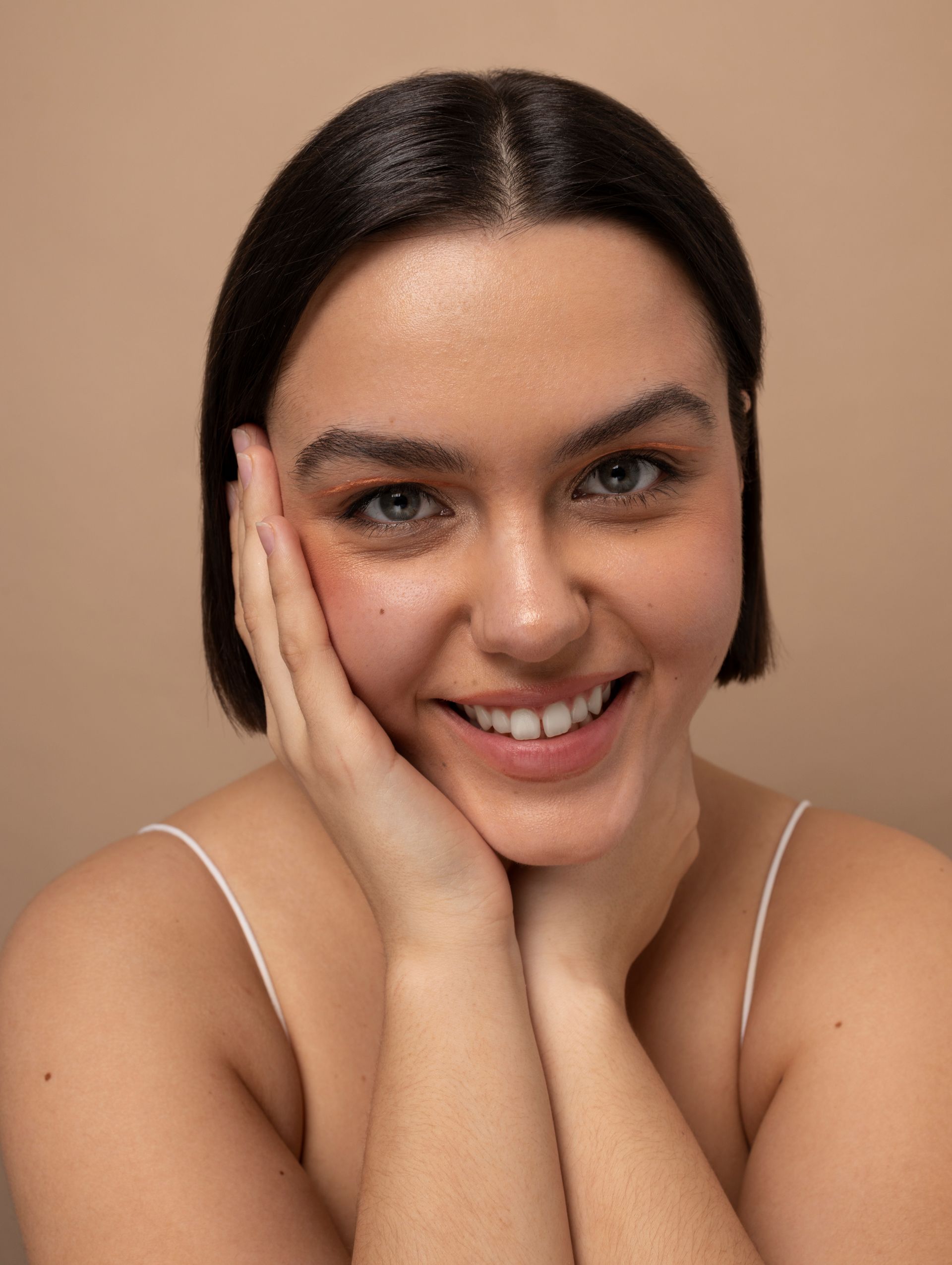 a woman is smiling with her hand on her face .