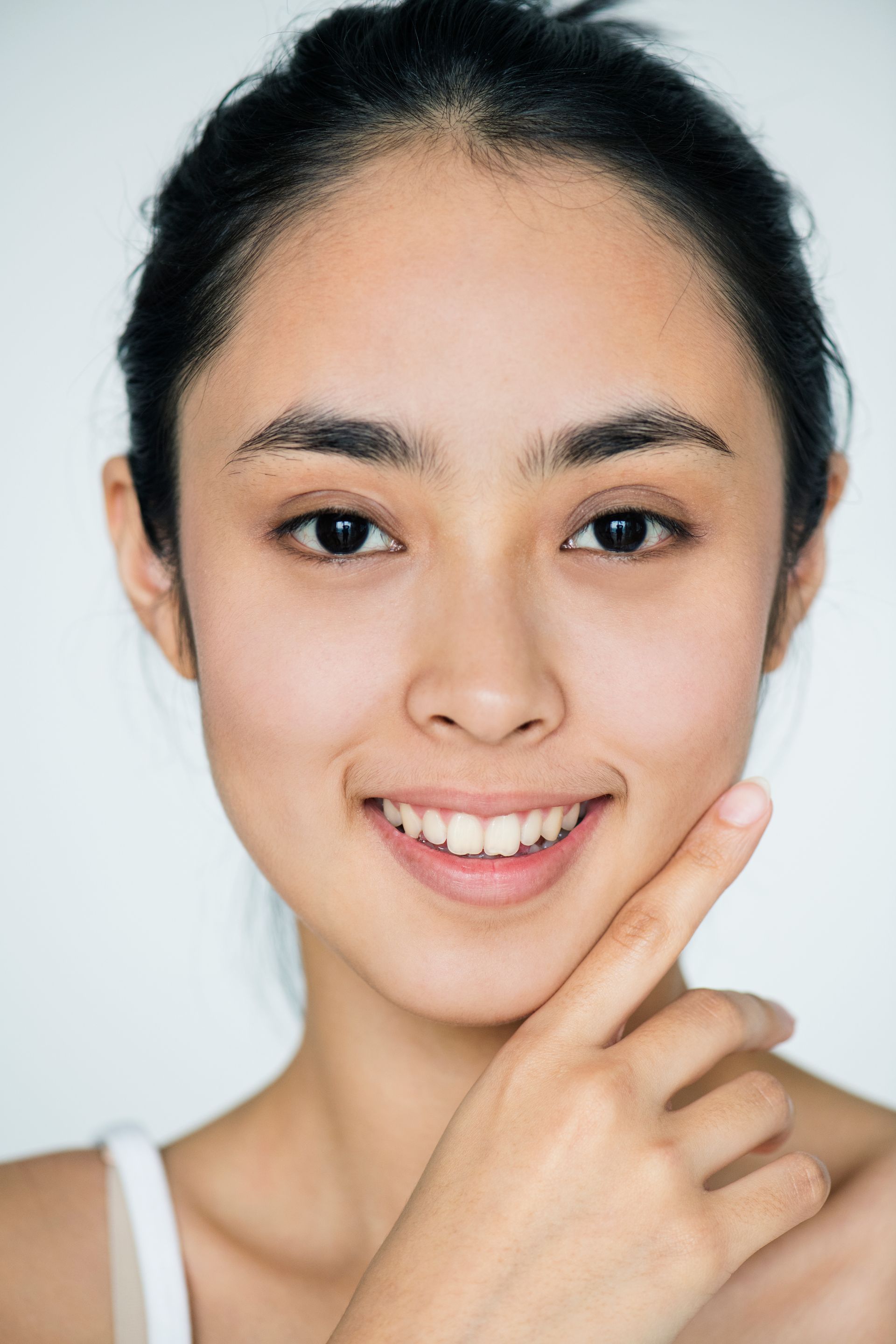 a woman is smiling and touching her face with her finger .