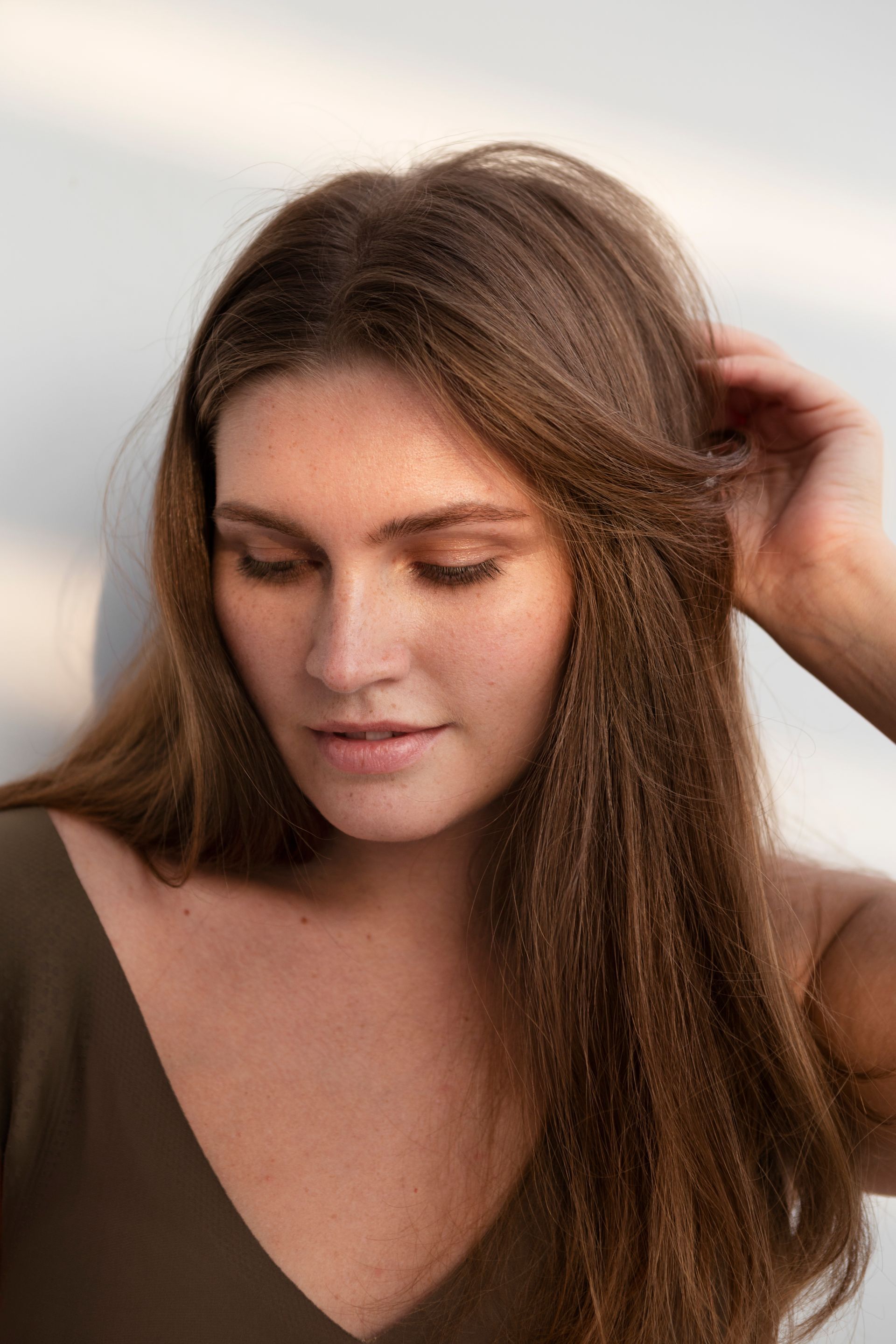 a woman with long brown hair is holding her hair in her hand .
