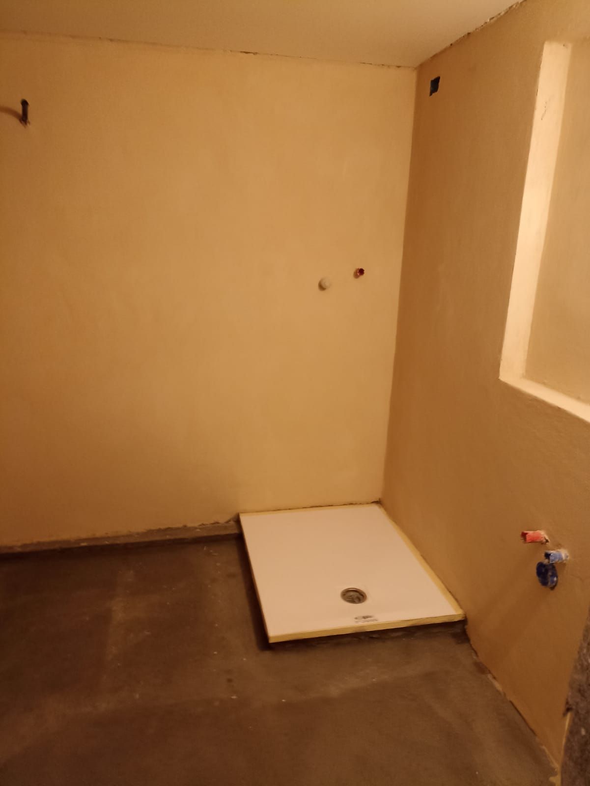 Angolo bagno vuoto color beige con piatto doccia e finestra bianchi.
