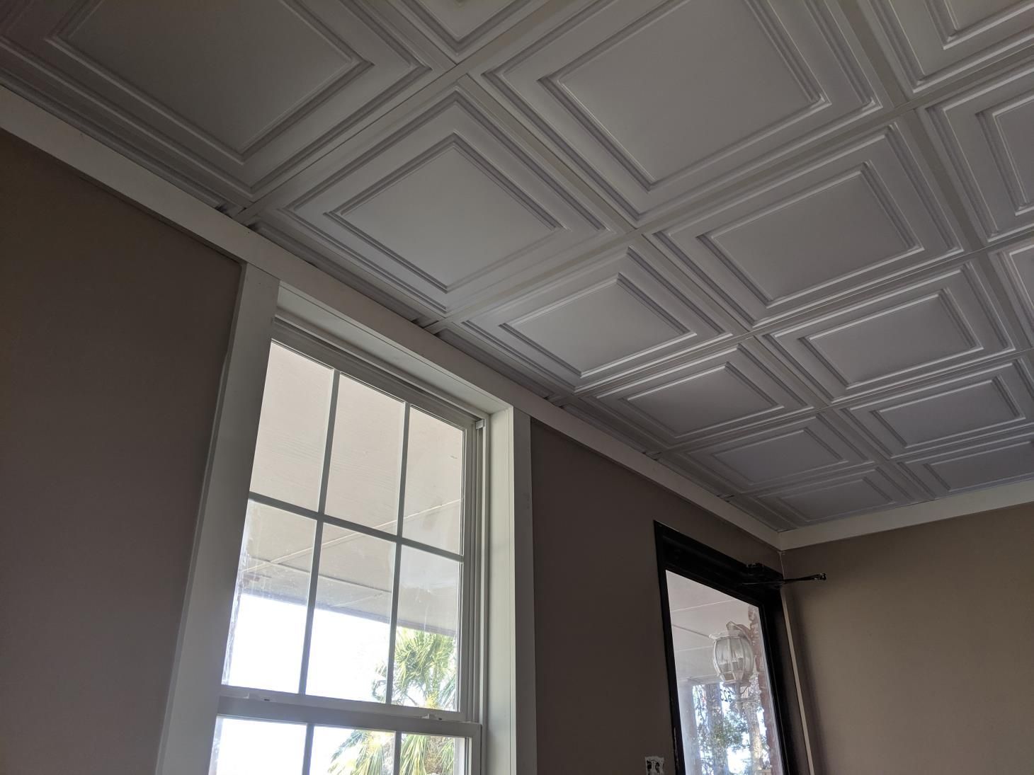 A room with a tiled ceiling and two windows.