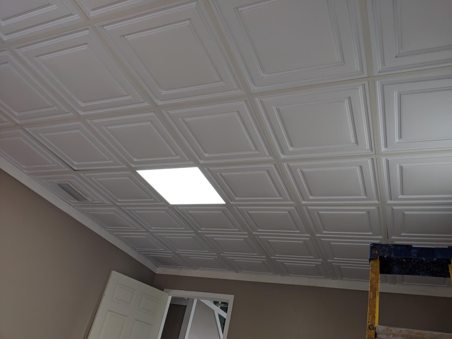 A room with a tiled ceiling and a light on the ceiling.