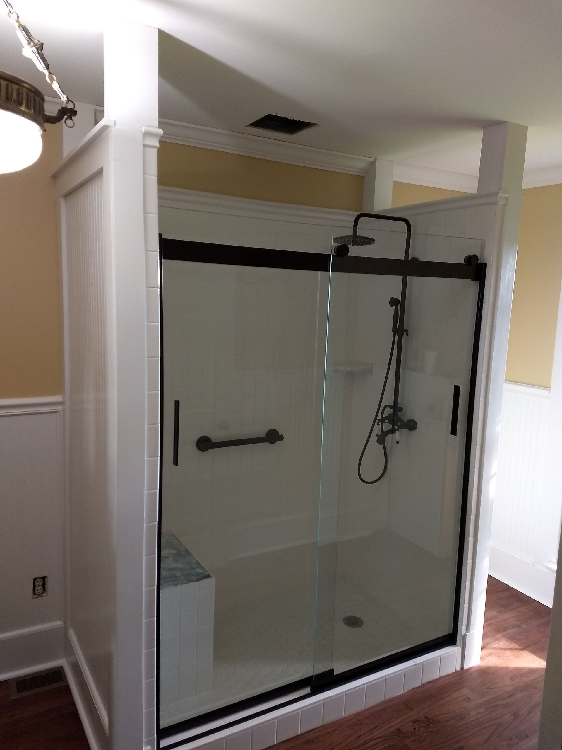 A bathroom with a sliding glass shower door and a shower head.