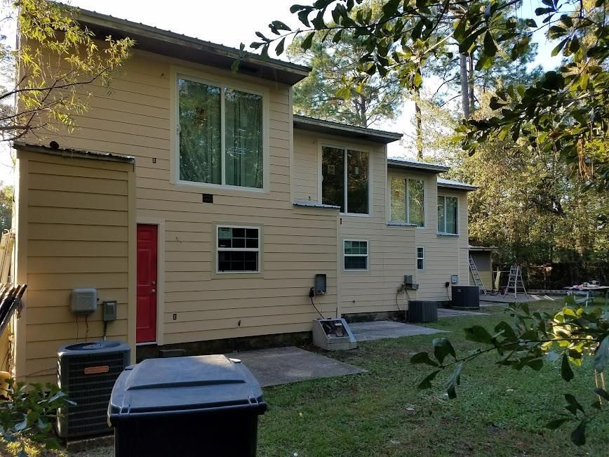 The back of a house with a red door and a lot of windows.