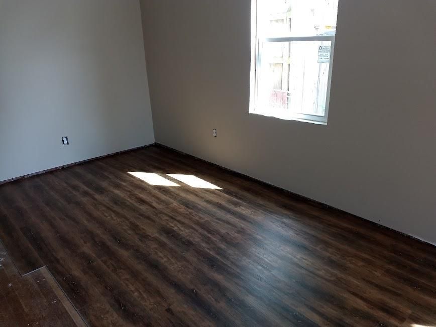 An empty room with hardwood floors and a window.