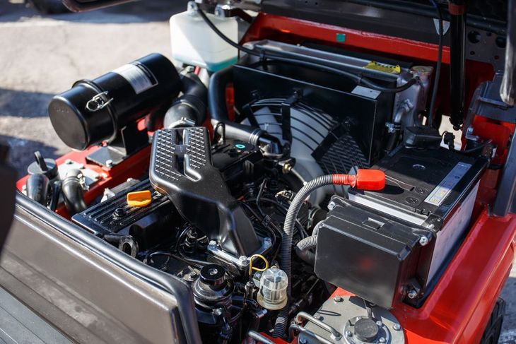 Open car engine bay with black components and red body panels