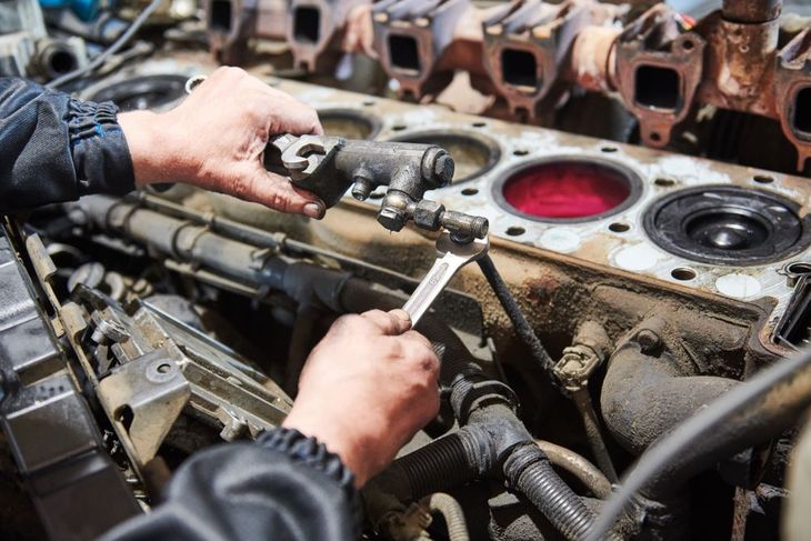 Mechanic using tools to repair an engine block in an auto workshop