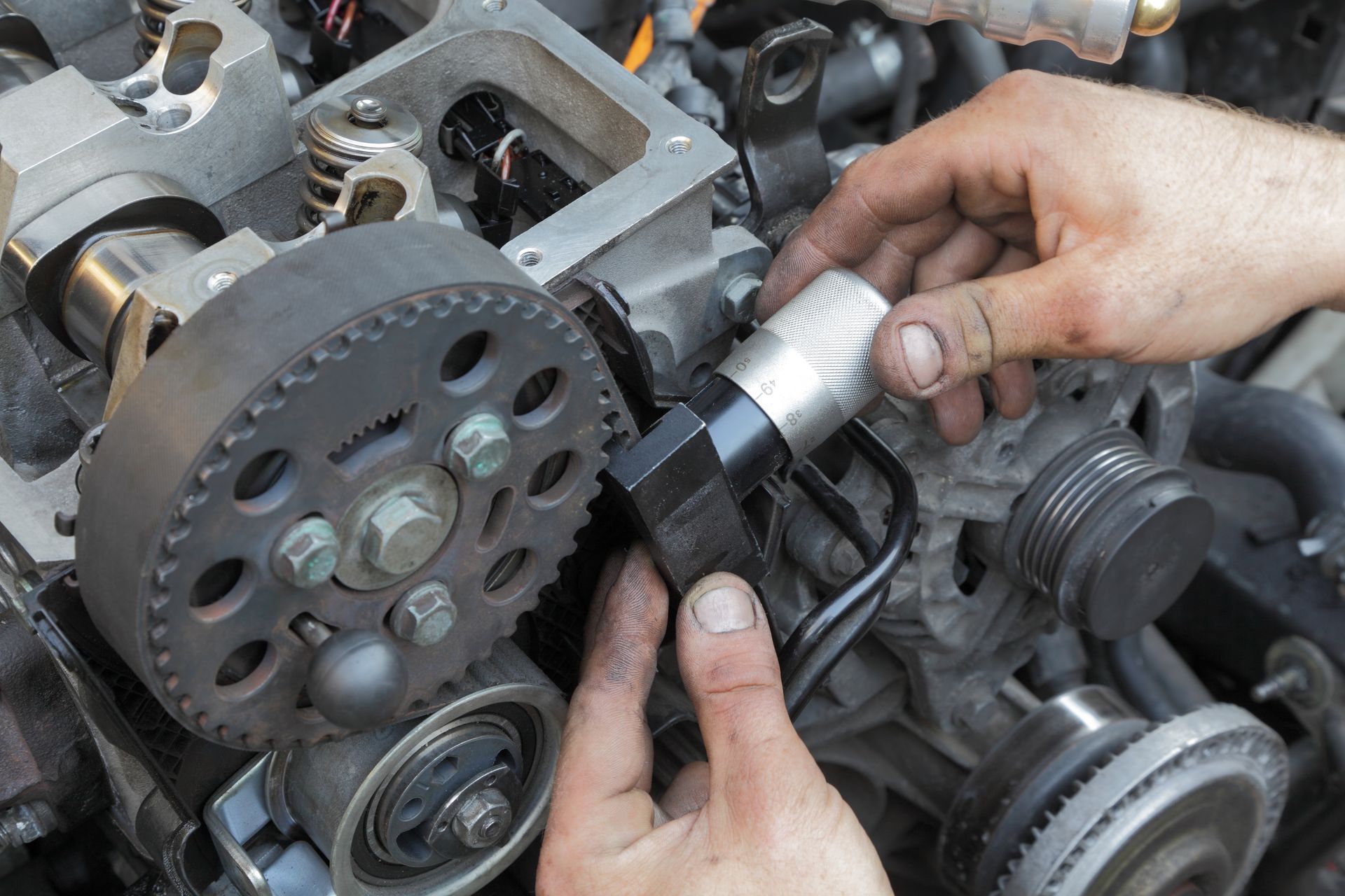 Hands using a socket wrench to adjust a car engine pulley and belt assembly