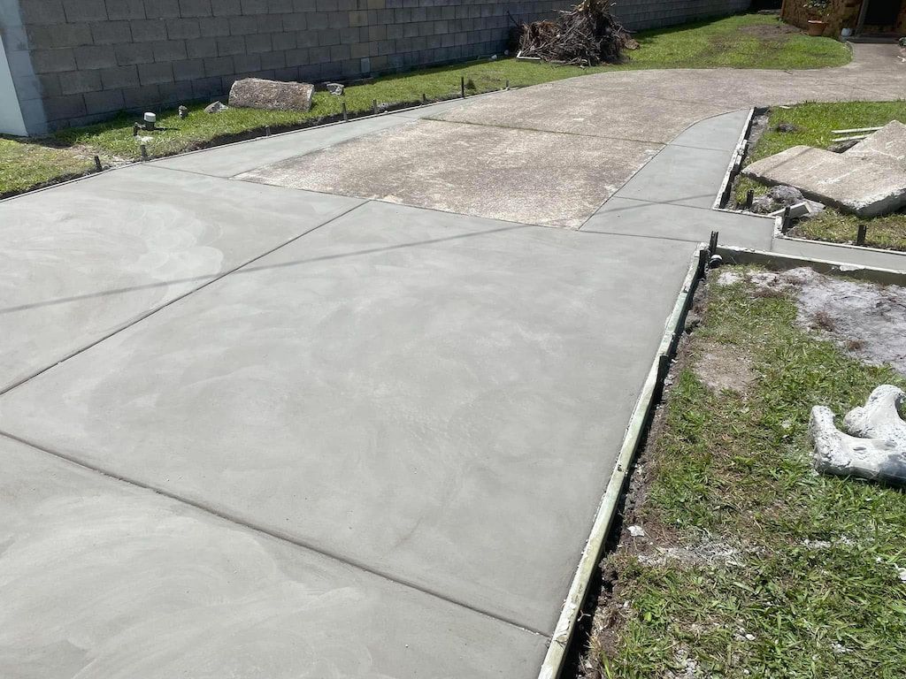 A concrete driveway is being built in the backyard of a house.