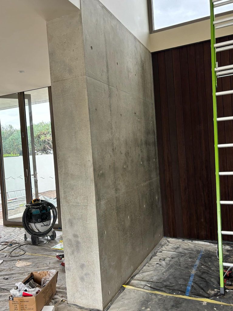 A ladder is sitting next to a concrete wall in a room.
