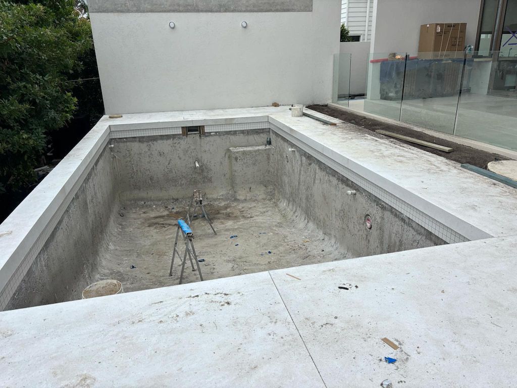 An empty swimming pool is being built on the roof of a building.