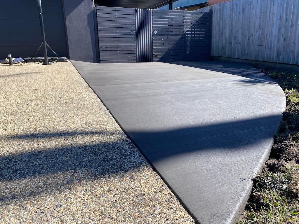 A concrete walkway with a wooden fence in the background.