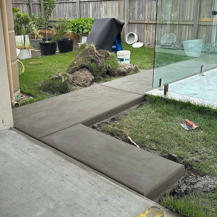 A concrete walkway is being built in a backyard