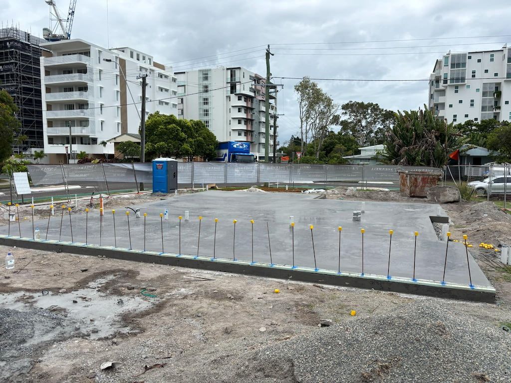 A construction site with a lot of concrete and buildings in the background.
