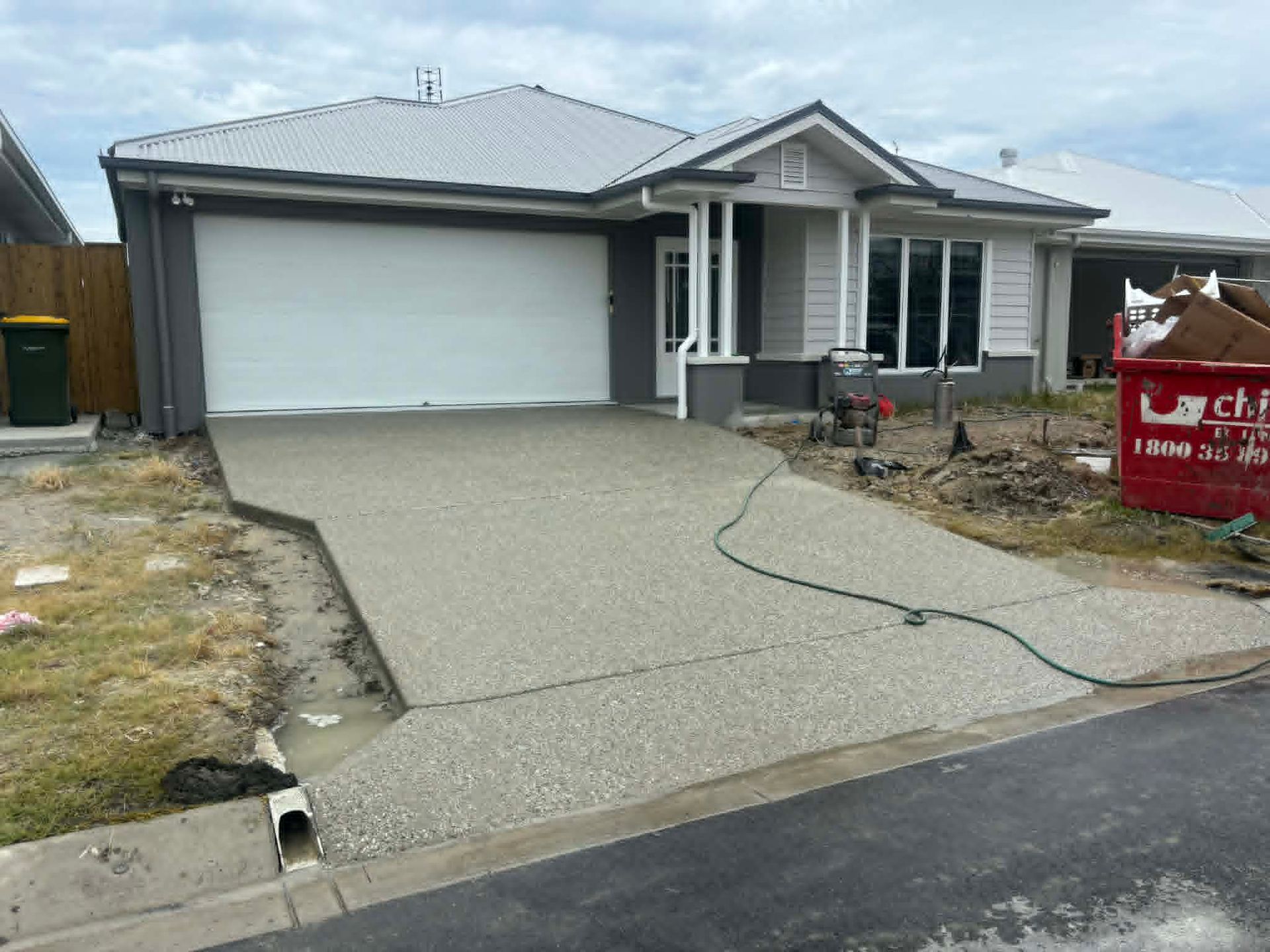 New single-story house with a double garage and fresh concrete driveway in a suburban neighborhood