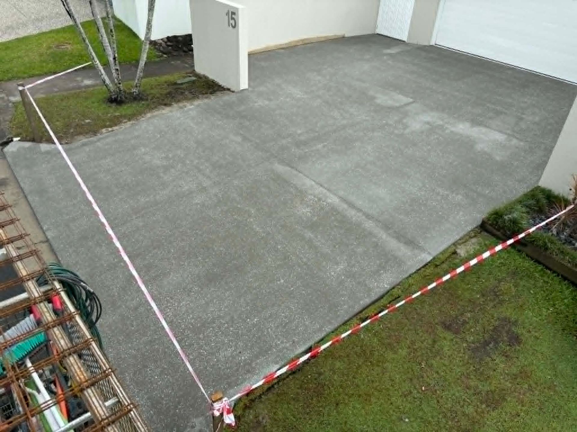 Cordoned-off concrete driveway beside a white building and green lawn