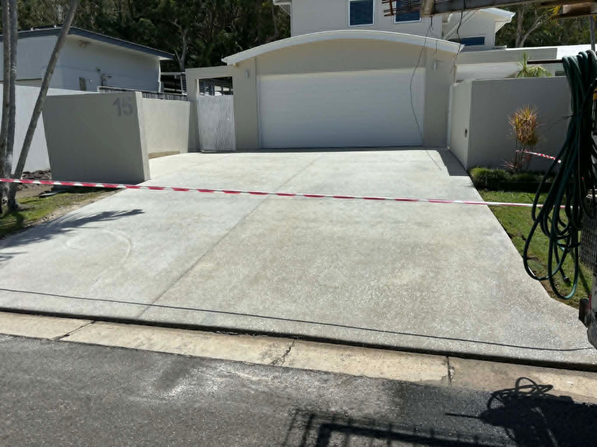 Concrete driveway leading to a white garage, blocked by red caution tape across the entrance.