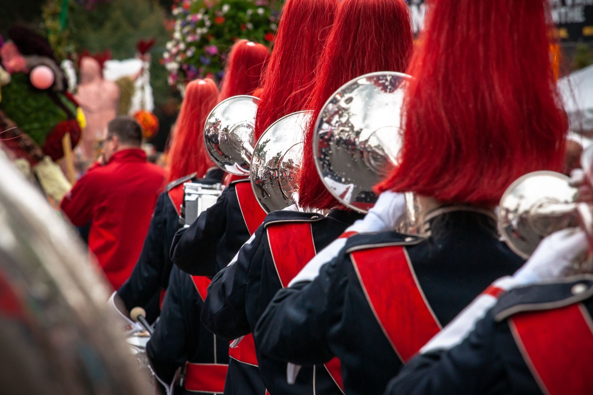 A marching band with red hair is playing instruments in a parade.