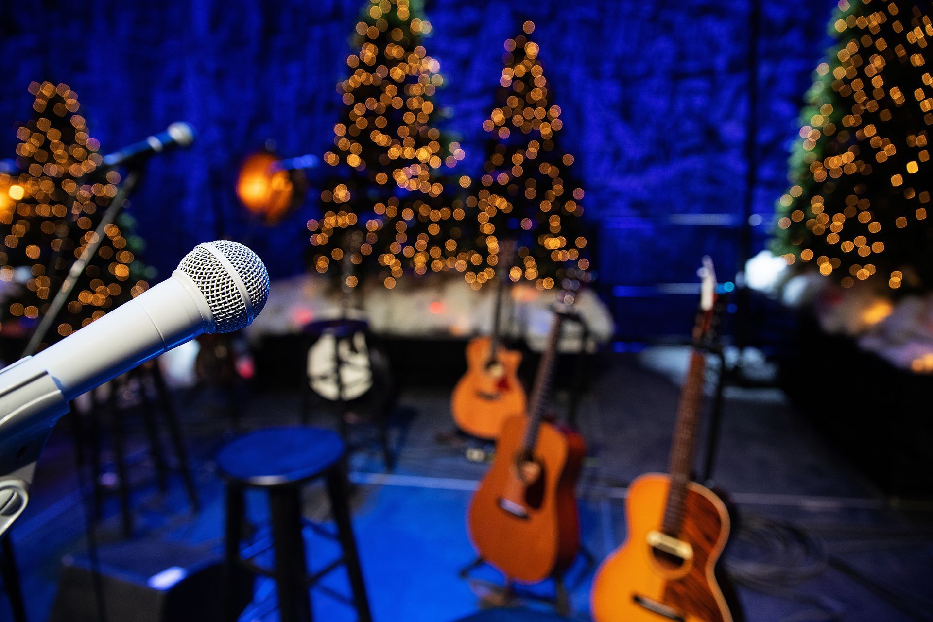 Microphone on stage with guitars, Christmas trees in background.