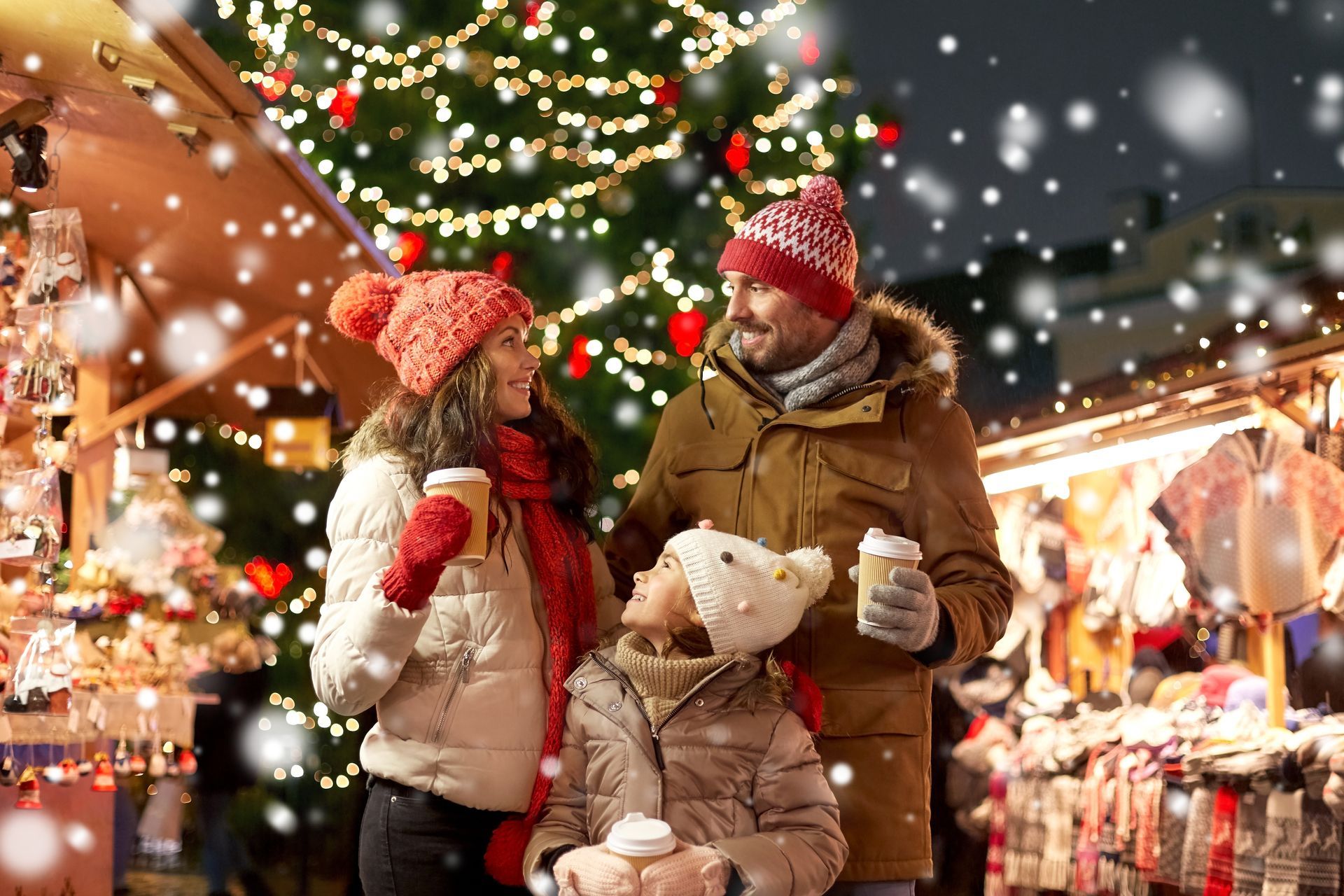 A family is standing in front of a christmas tree at a christmas market.