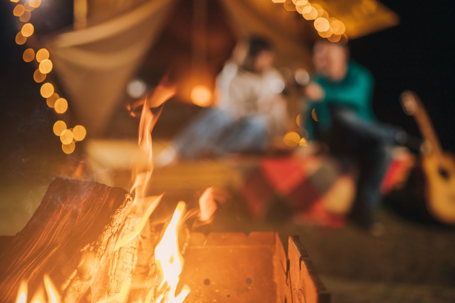 A group of people are sitting around a campfire at night.