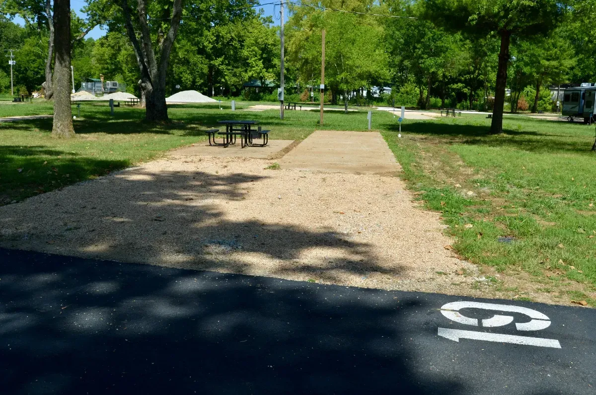Campsite with gravel, picnic table, asphalt road marked 