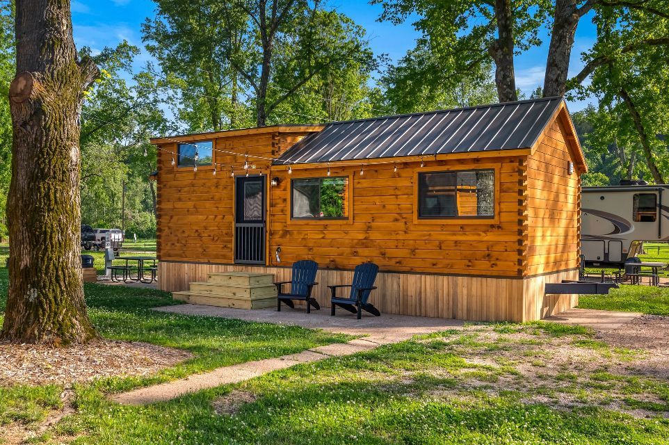 A small wooden house is sitting in the middle of a grassy field.