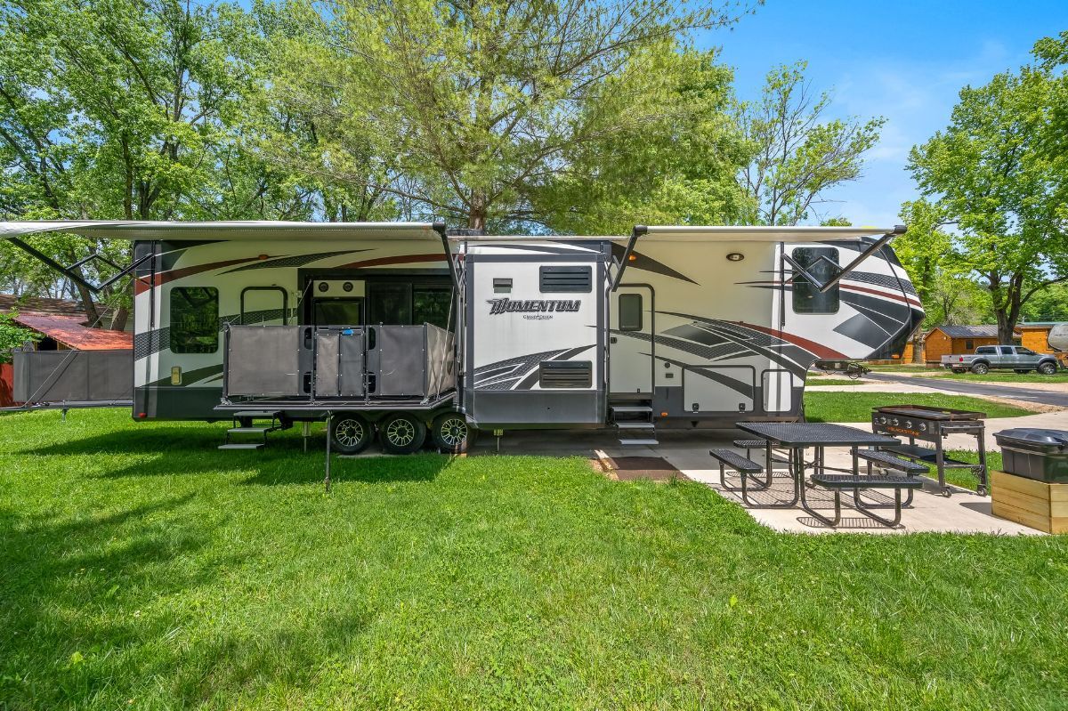 Large RV parked on grassy lot with picnic table.
