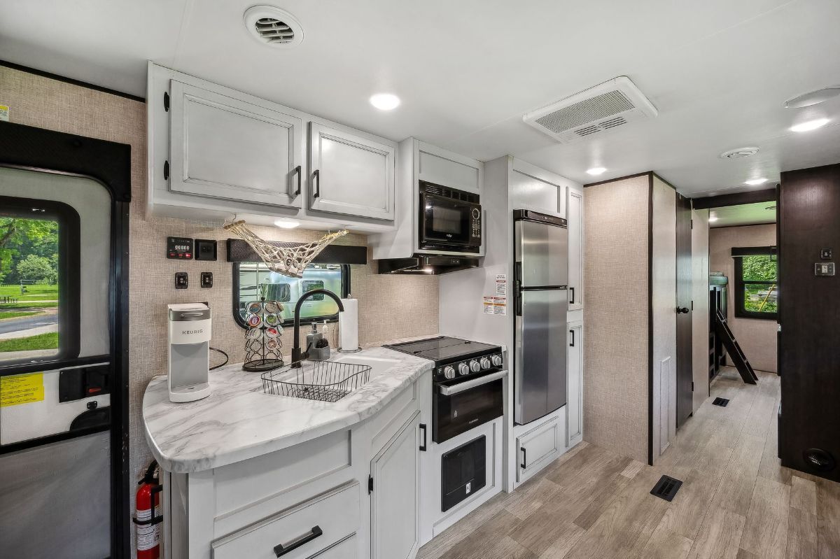 RV kitchen with light cabinets, appliances, and a window.