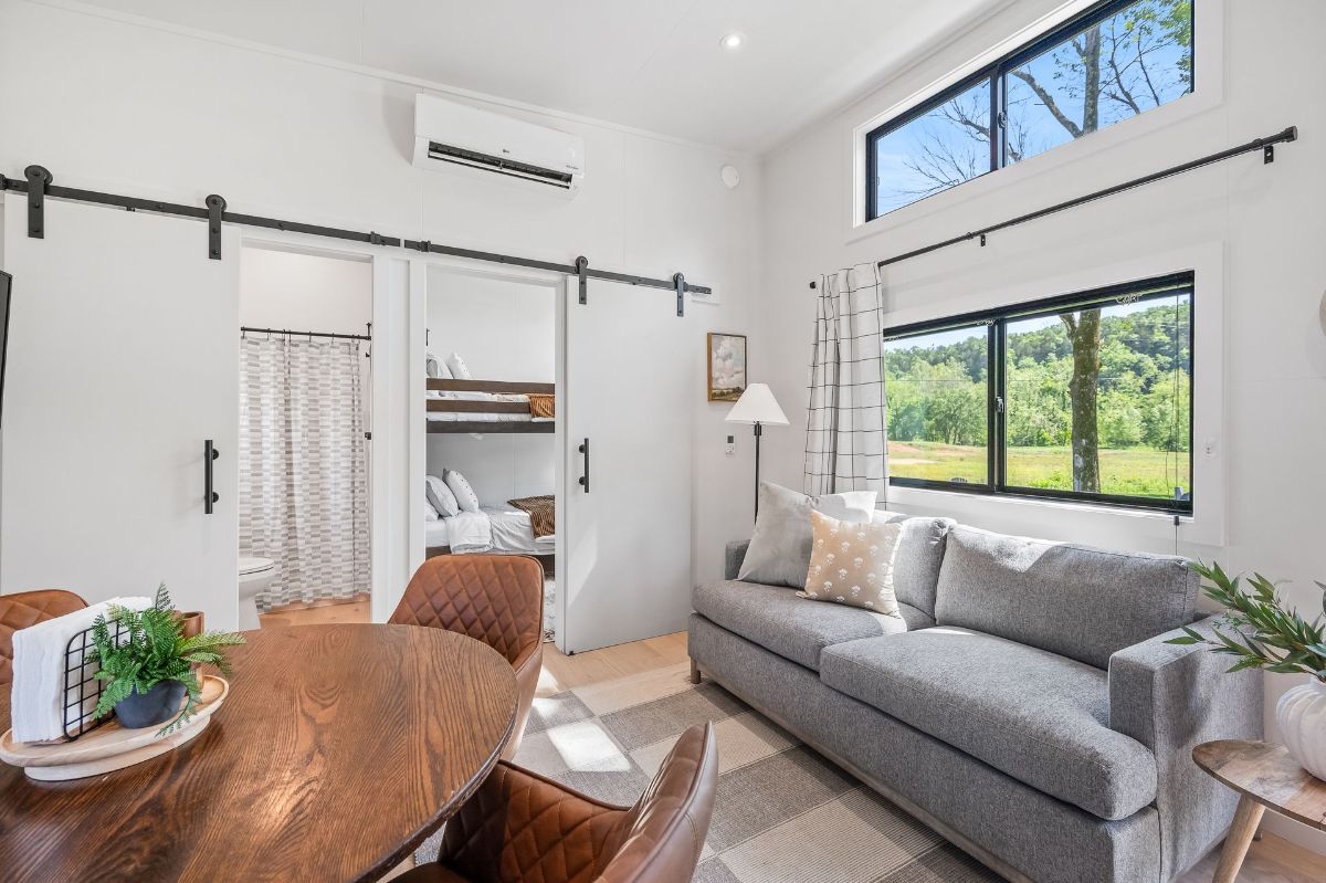 Cozy living room with a sofa, dining table, and sliding barn doors leading to a bunk bed room.