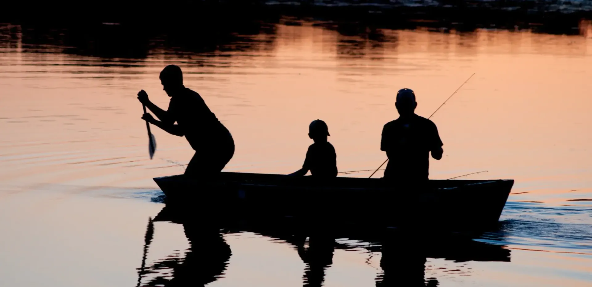 A group of people are fishing in a boat on a lake.