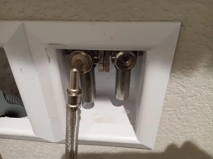 Laundry hookup with cold water valve and supply hose, hot water valve is missing a hose.