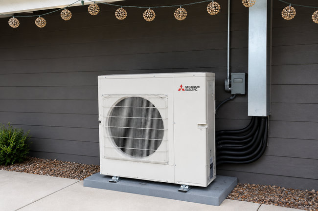 Water heater and furnace in a cramped utility closet with exposed pipes and ductwork