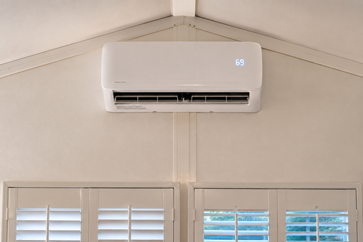 Wall-mounted furnace in a closet with open white doors and a floor vent in a hallway.