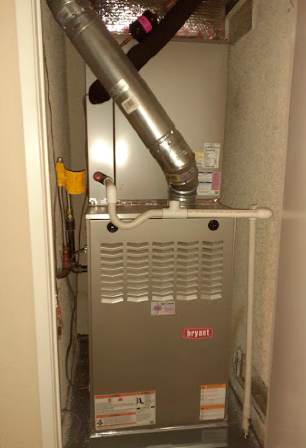 Basement furnace with metal vent pipe in a narrow utility closet