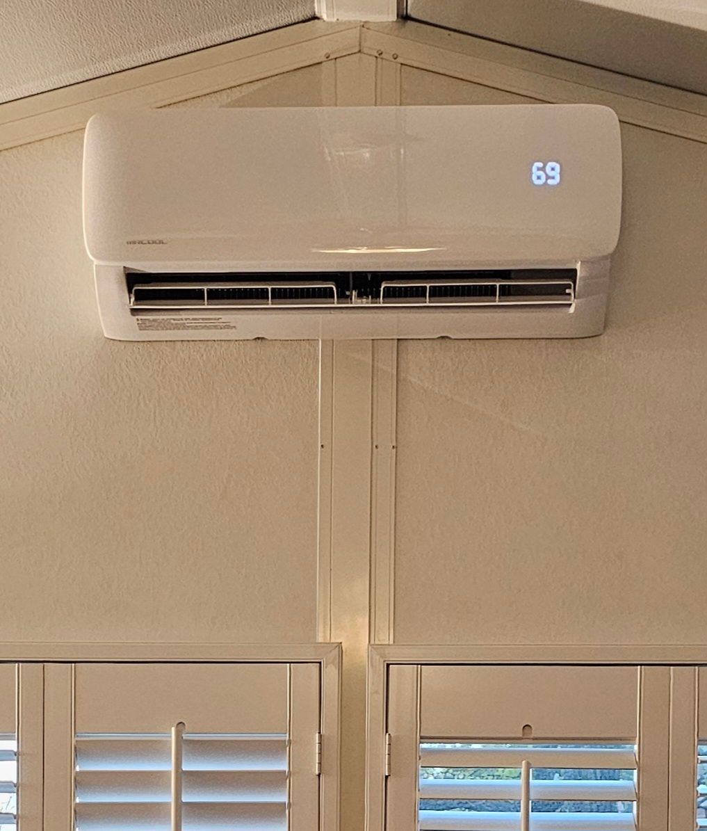 White wall-mounted air conditioner above windows, displaying 69.