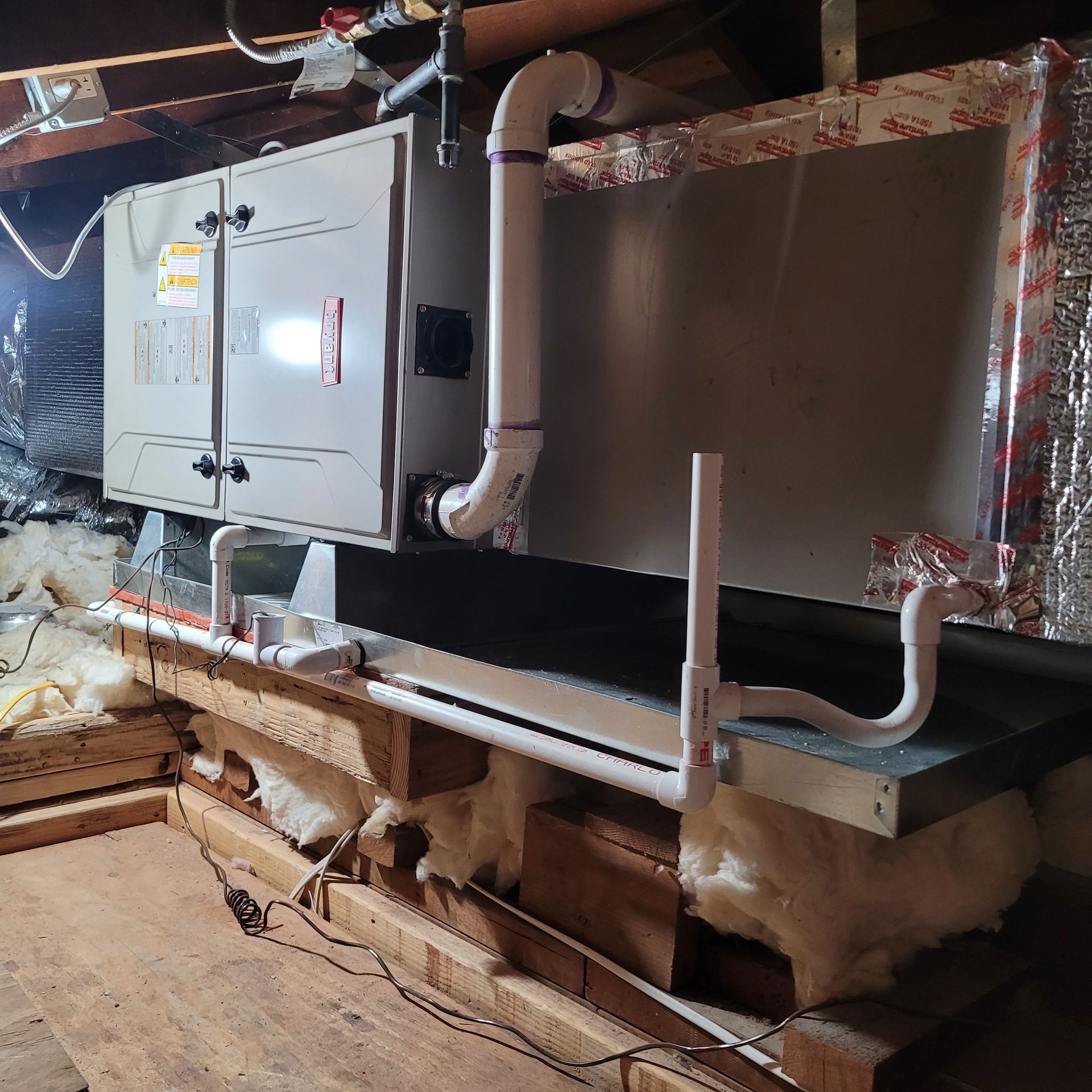 Attic HVAC unit with insulated ductwork and exposed framing