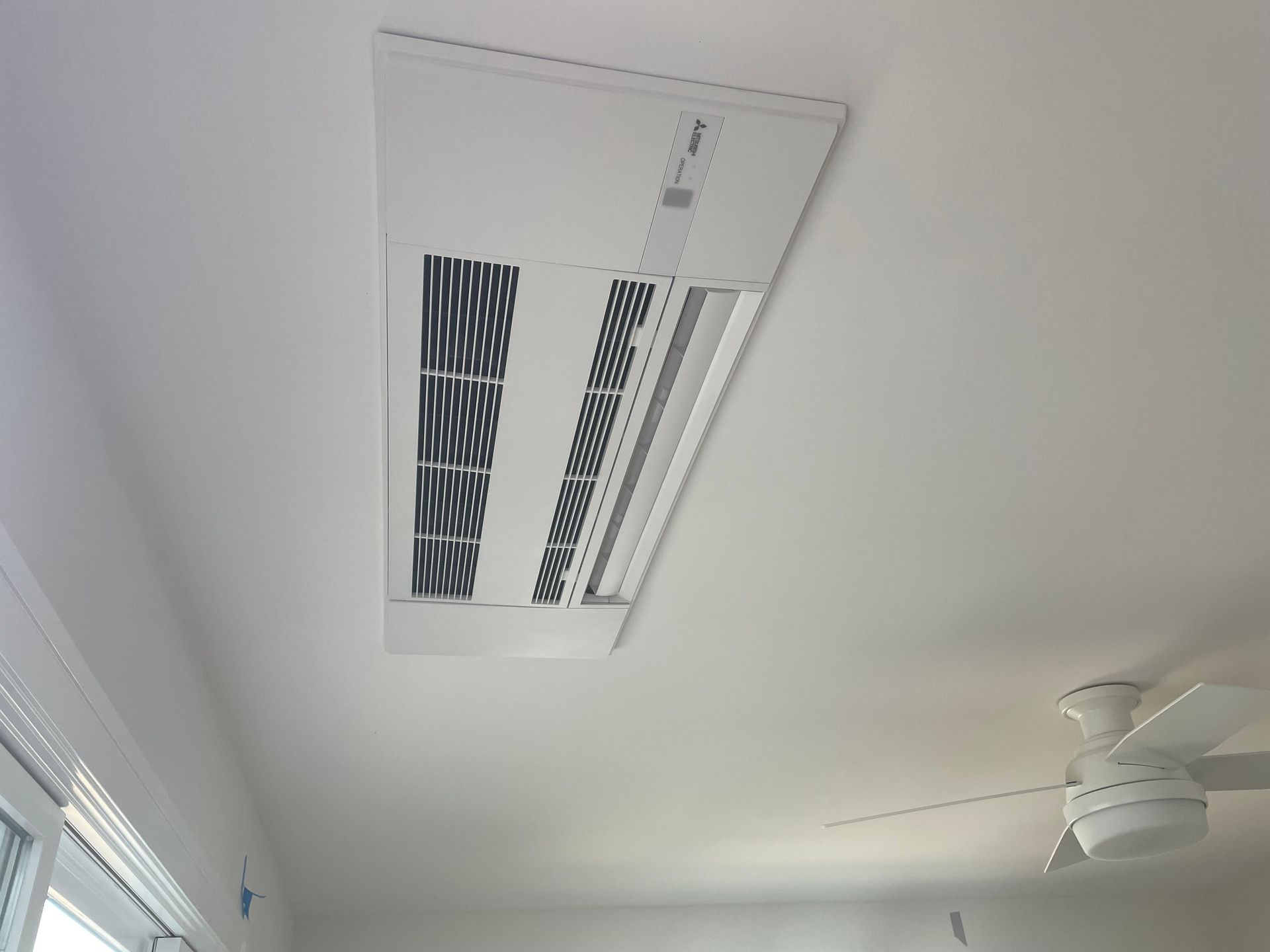 Ceiling air vent and white ceiling fan in a bright room
