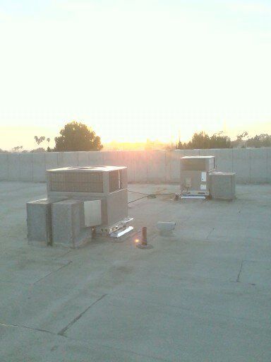 Rooftop HVAC units at sunset with a low wall and open concrete surface