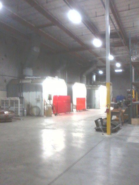 Empty warehouse interior with red cabinets, bright lights, and a yellow support pole