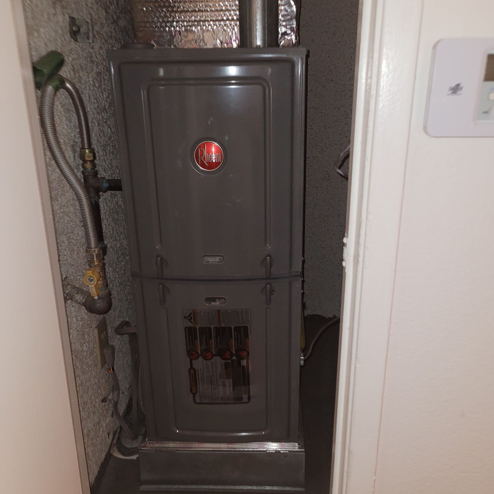 Gray electrical breaker panel with an open lower compartment in a narrow hallway.