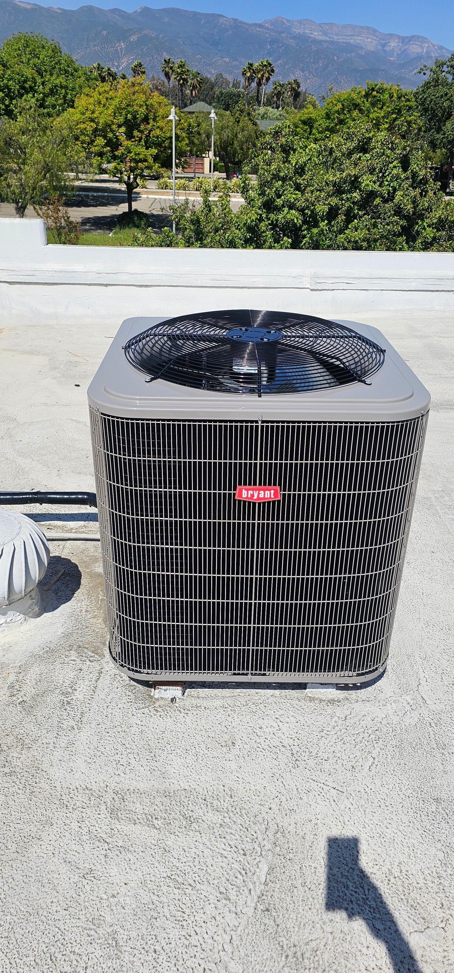 Outdoor air conditioner condenser unit on concrete pad with mountains and trees in the background