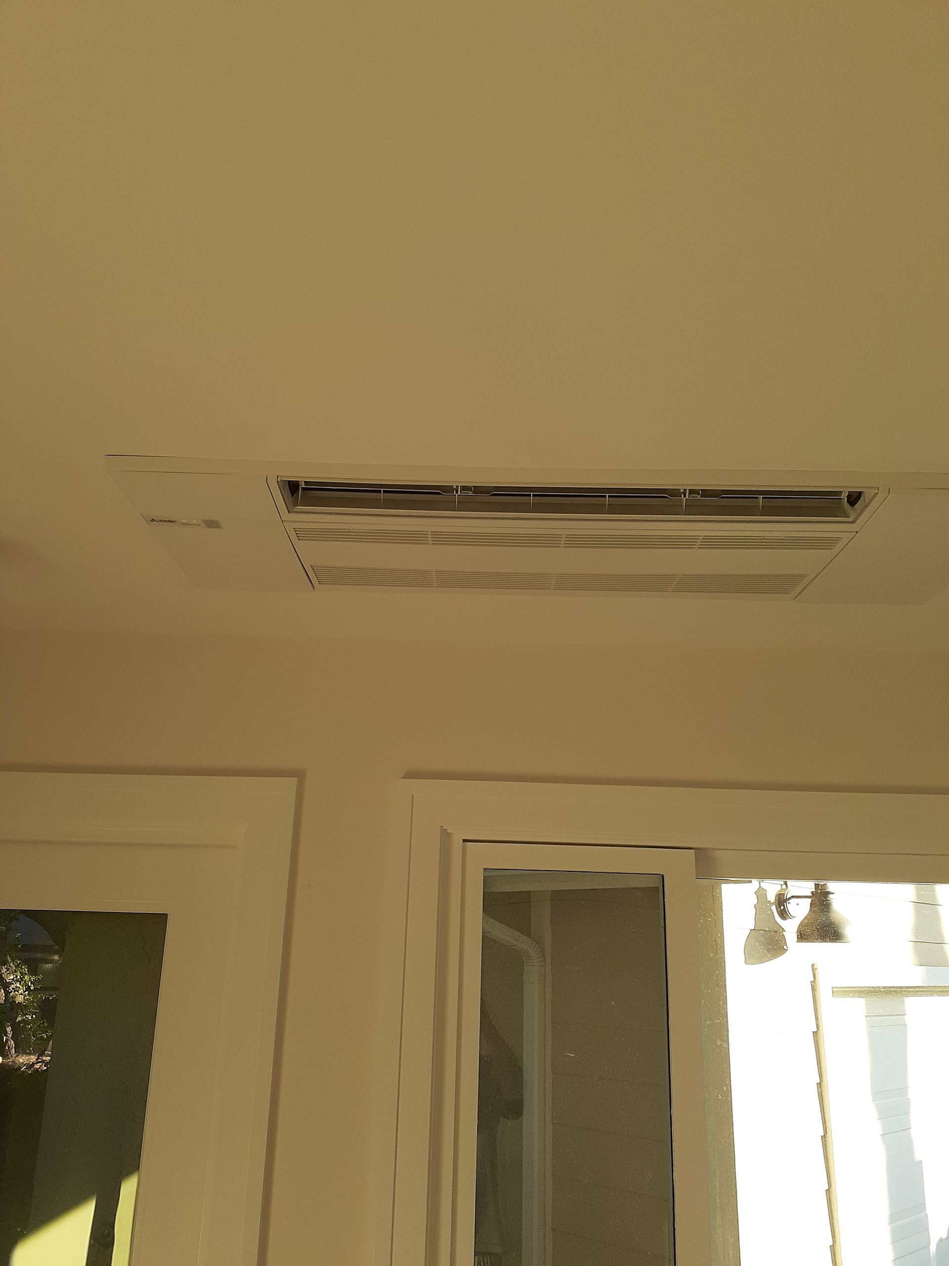 Ceiling air vent above a doorway, with a wall and window below.