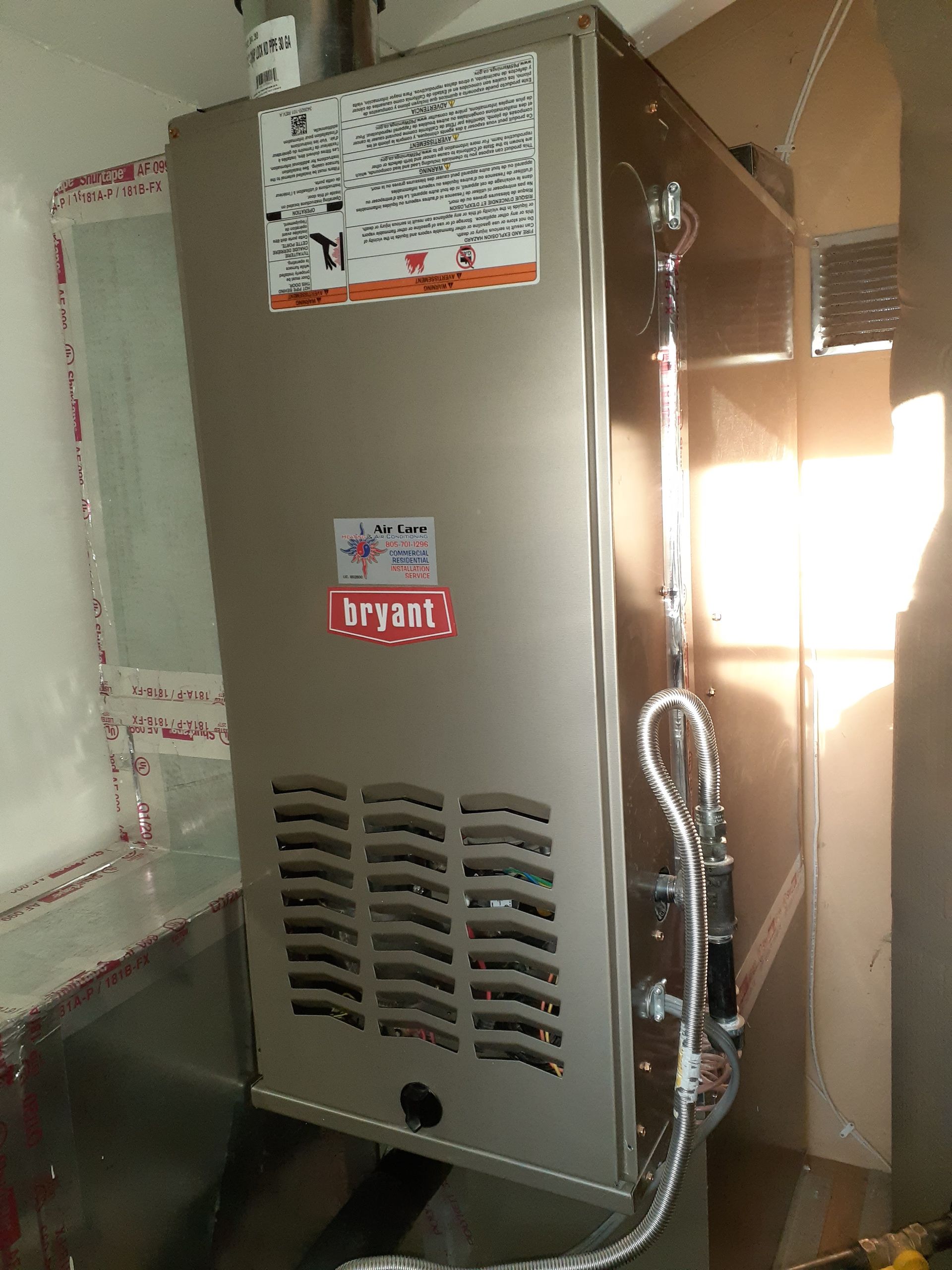 Gray furnace unit with vent slats and copper pipes in a utility closet