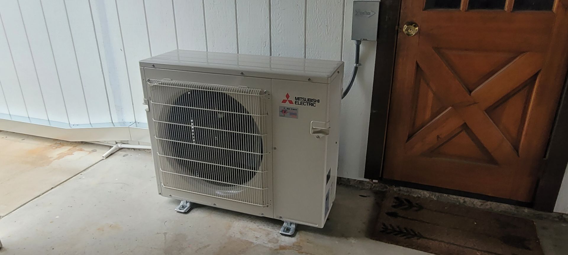 Portable air conditioner unit on wheels beside a wooden door indoors